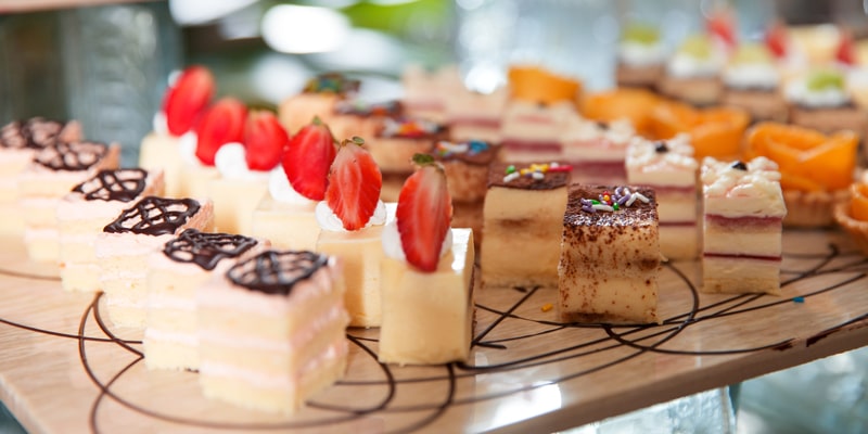 Una foto con varios mini tiramisus de diferentes sabores sobre una tabla de madera con chocolate rociado. 