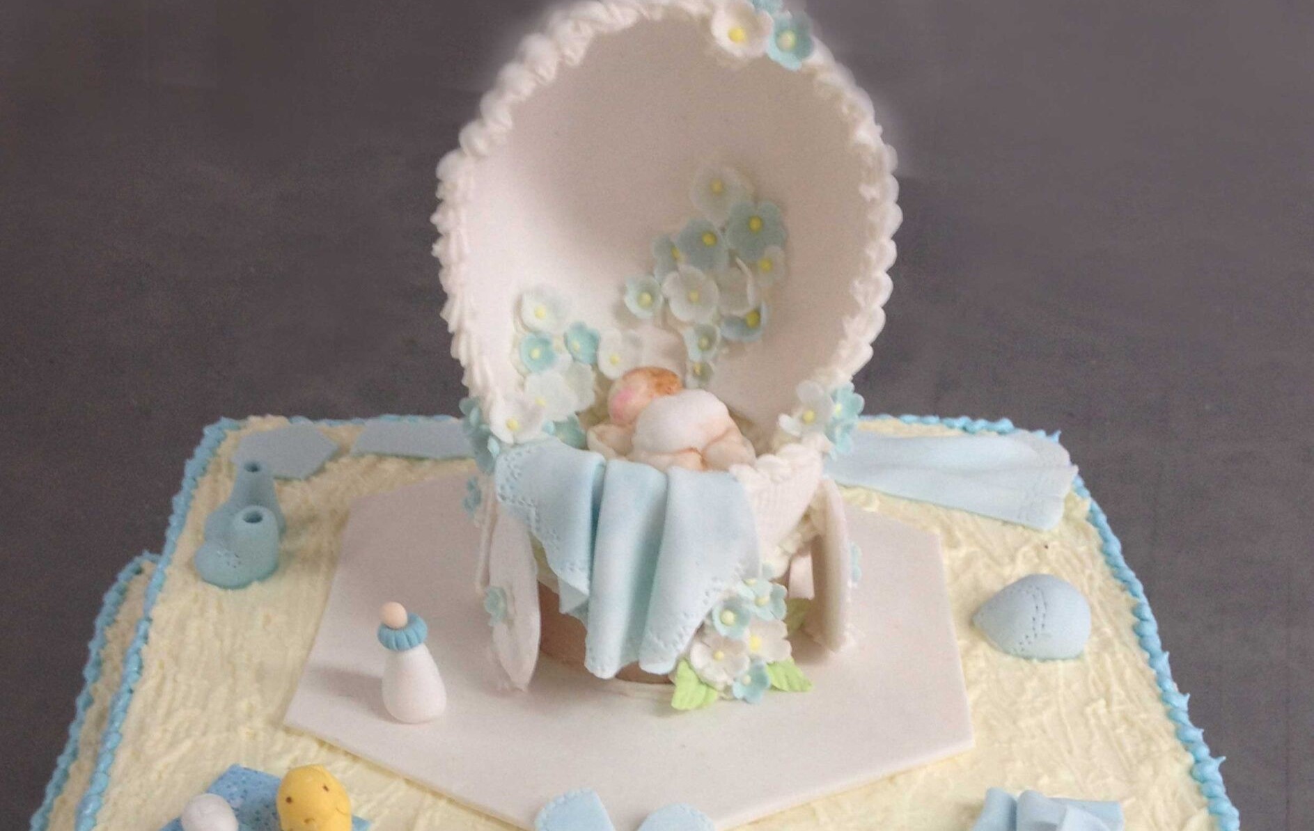 Ponque con glaseado blanco y decoraciones azules, también incluye decoraciones en fondant con temática de bebés.